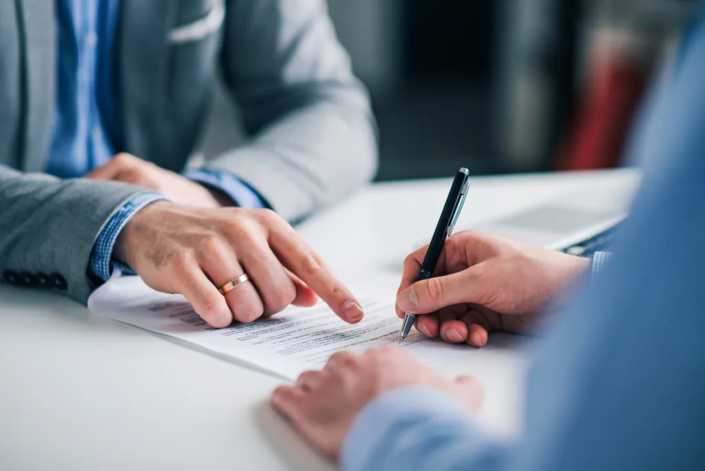 Professionnels indiquant l'emplacement de signature d'un contrat de responsabilité civile